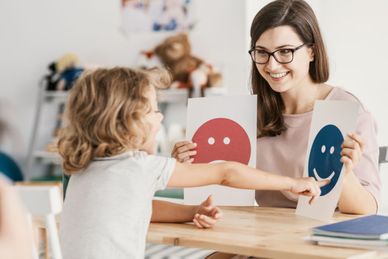 Educadora trabajando reconocimento de emociones con un niño para prevenir la sobrecarga emocional infantil