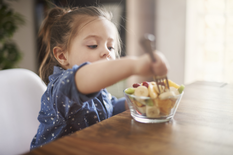 Niña comiendo frutas como parte de una alimentación infantil balanceada